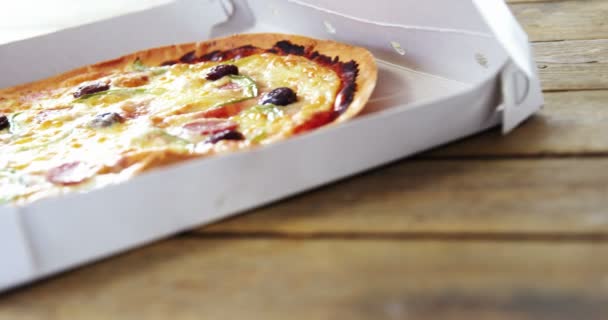 Pizza en caja de pizza sobre mesa de madera — Vídeo de stock