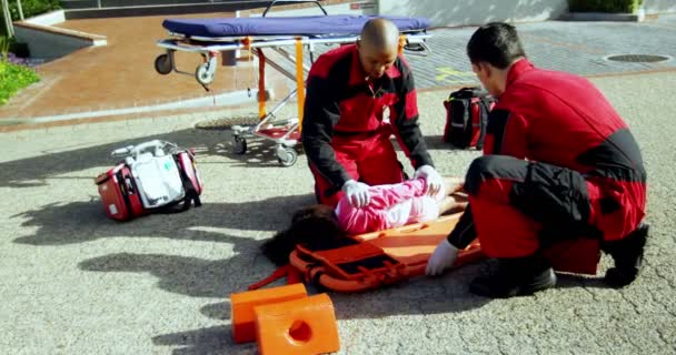 Paramédicos poniendo a una chica lesionada en un tablero — Vídeos de Stock