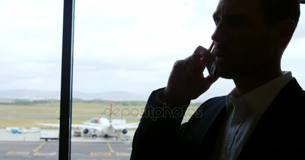 Бизнесмен разговаривает по мобильному телефону в аэропорту — стоковое видео