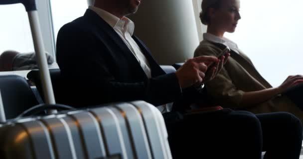 Бизнесмен пишет смс на мобильный телефон во время ожидания в аэропорту — стоковое видео