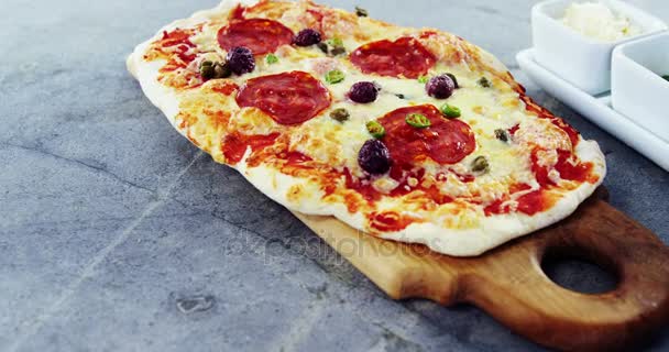 Gebakken met olijven en peperoni pizza toppings geserveerd op hakken bestuur — Stockvideo