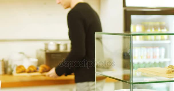 Homem guardando bandeja de croissants em vitrine de café — Vídeo de Stock