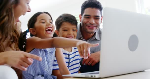 Met laptop in de woonkamer en gelukkige familie — Stockvideo