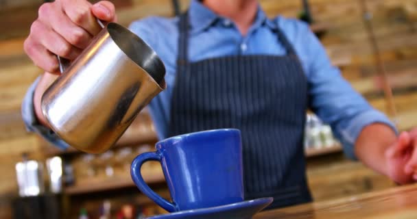 Camarero vertiendo leche en el café en el mostrador — Vídeos de Stock