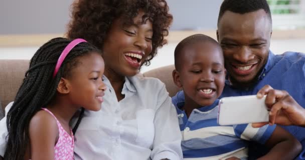 Família sentada no sofá e usando telefone celular — Vídeo de Stock