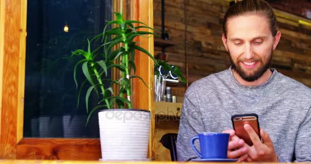 Hombre usando el teléfono móvil mientras toma café — Vídeo de stock