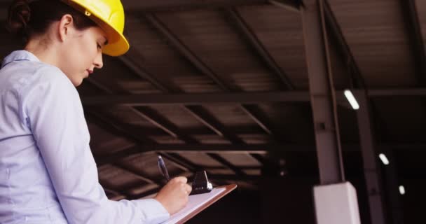 Female supervisor maintaining record on clipboard — Stock Video