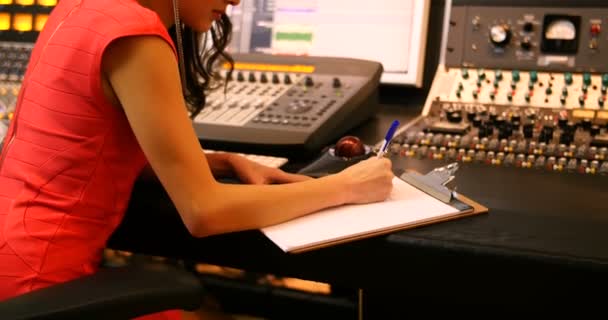 Female audio engineers writing on clipboard — Stock Video