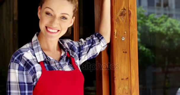 Красивая официантка, стоящая у дверей кафе — стоковое видео