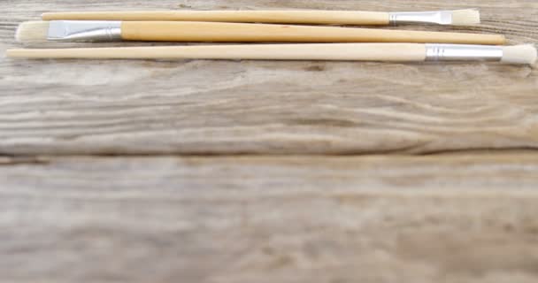 Various paint brushes on wooden table — Stock Video