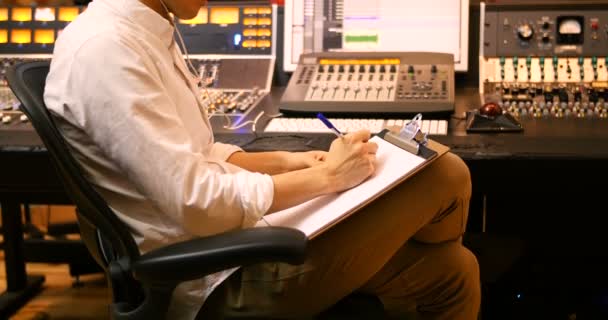 Male audio engineers writing on clipboard — Stock Video