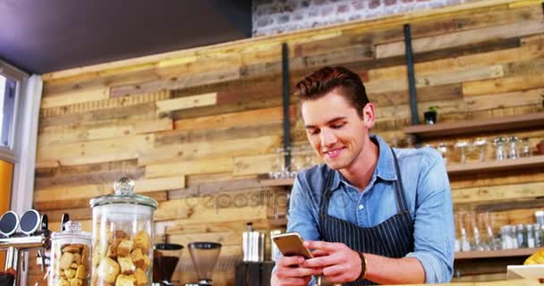 Mężczyzna kelner przy użyciu telefonu komórkowego w kasie — Wideo stockowe