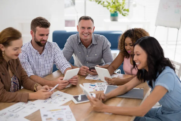 Team van leidinggevenden met behulp van elektronische apparaten in het kantoor — Stockfoto