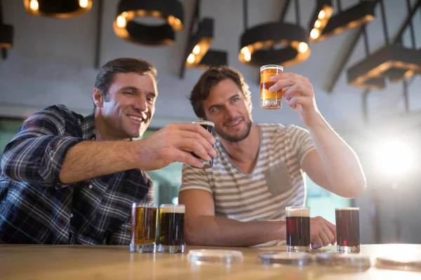 Amigos segurando copo de cerveja no balcão do bar — Fotografia de Stock