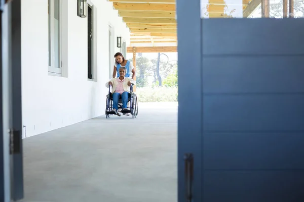 Medico spingendo felice paziente anziano in sedia a rotelle — Foto Stock