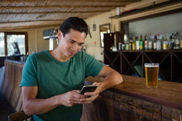 男人坐在酒吧柜台时使用电话 — 图库照片