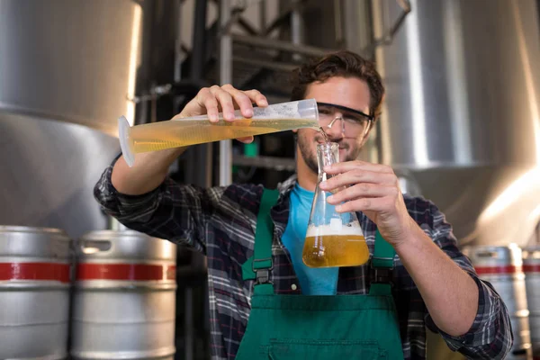 Trabalhador sorrindo derramando cerveja em copo — Fotografia de Stock