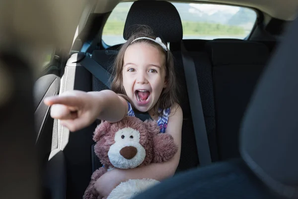 Heyecanlı kız arabaya el hareketi sırasında oyuncak ayı holding — Stok fotoğraf
