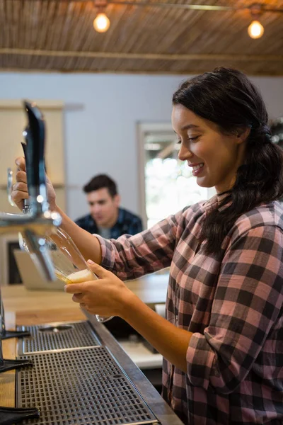 Barmaid pouring beer from tap in glass — Stock Photo, Image
