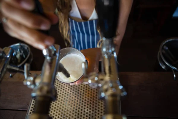 Барменша наливает пиво из крана в стекло — стоковое фото
