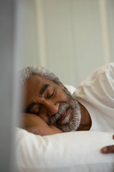 Старший мужчина спит на кровати в спальне — стоковое фото