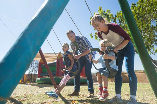 Ouders kinderen swingen op speelplaats — Stockfoto