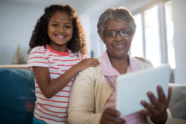 Enkelin und Großmutter halten Tablet in der Hand — Stockfoto