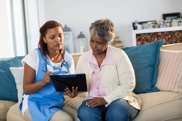 Arts medicatie op Klembord uit te leggen aan vrouw — Stockfoto