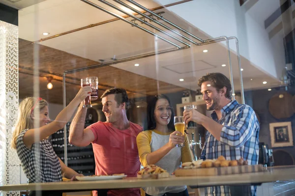 Vrolijke vrienden het roosteren van drank in restaurant — Stockfoto
