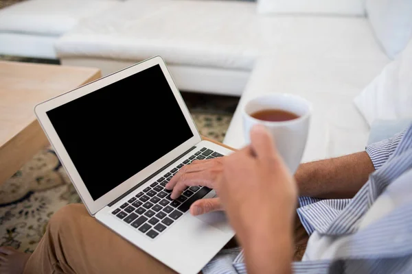 コーヒーを持ちながらノート パソコンを使用している人 — ストック写真