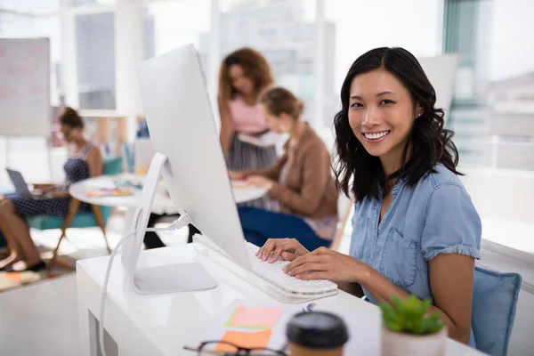 Женщина-руководитель, работающая за компьютером за столом в офисе — стоковое фото