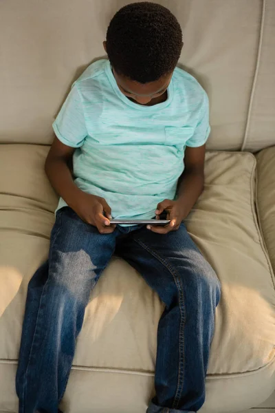 Pojke med hjälp av mobiltelefon i vardagsrummet — Stockfoto