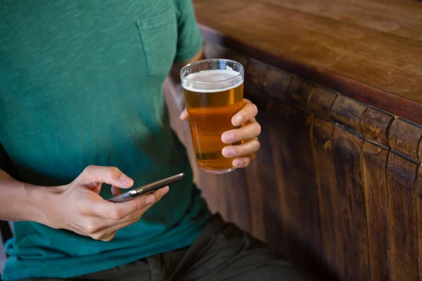 Homem usando telefone enquanto bebe cerveja — Fotografia de Stock
