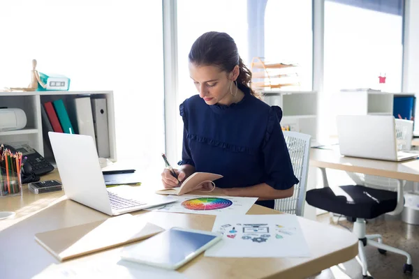 Vrouwelijke uitvoerend schrijven in dagboek aan balie — Stockfoto