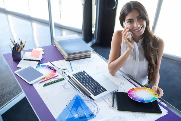 Female executive talking on mobile phone at her desk — Stock Photo, Image