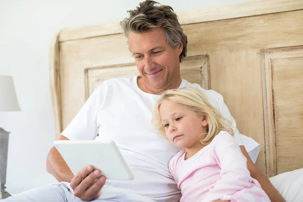 Far och dotter använder surfplatta på säng — Stockfoto