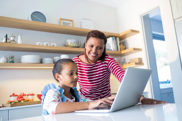 Mãe e filha usando laptop na bancada da cozinha — Fotografia de Stock