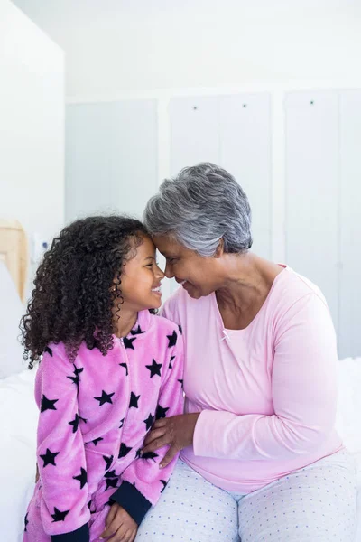 Barnbarn och mormor sitta ansikte mot ansikte på sängen — Stockfoto