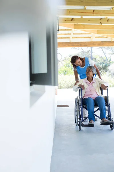 Лікар штовхає щасливого старшого пацієнта в інвалідному візку — стокове фото