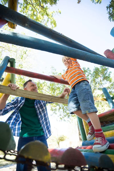 Father looking at son walking on jungle gym — Stock Photo, Image