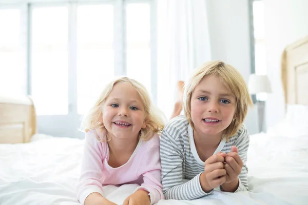 Geschwister entspannen sich auf Bett im Schlafzimmer — Stockfoto