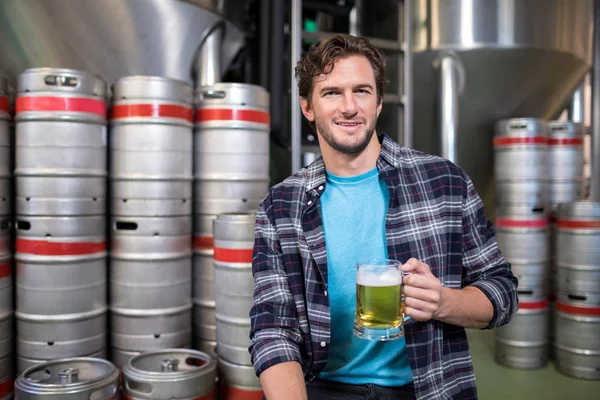 Trabalhador segurando copo de cerveja na fábrica — Fotografia de Stock