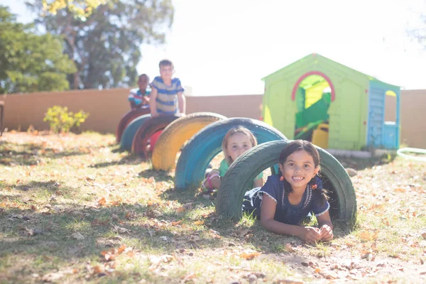 Dzieci bawiące się przez opony, na placu zabaw — Zdjęcie stockowe