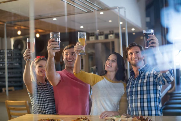 Vrolijke vrienden met hand opgeheven bedrijf bier — Stockfoto