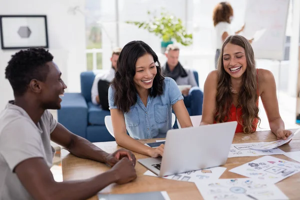 Compañeros de negocios discutiendo sobre portátil en la oficina — Foto de Stock