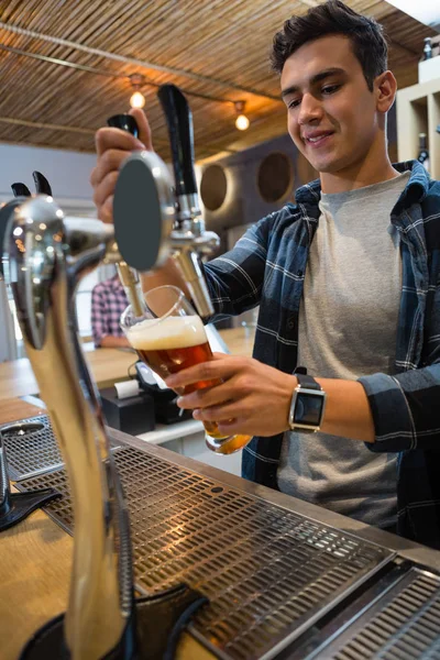 Bartender pouring beer from tap in glass — Stock Photo, Image