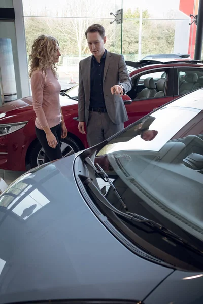 Cliente olhando para vendedor mostrando carro — Fotografia de Stock