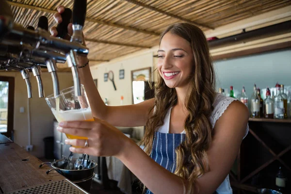 Barmaid pouring beer from tap in glass — Stock Photo, Image