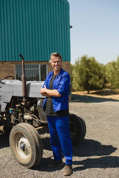 Travailleur debout avec les bras croisés près du tracteur — Photo