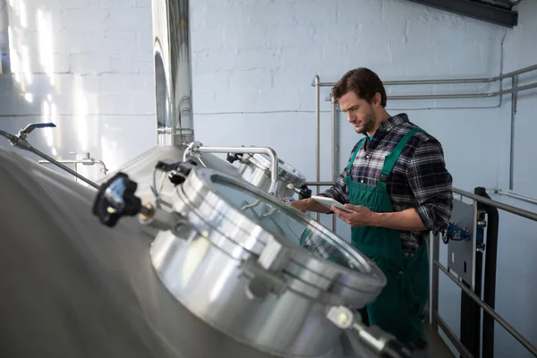 Worker using tablet while examining vat — Stock Photo, Image